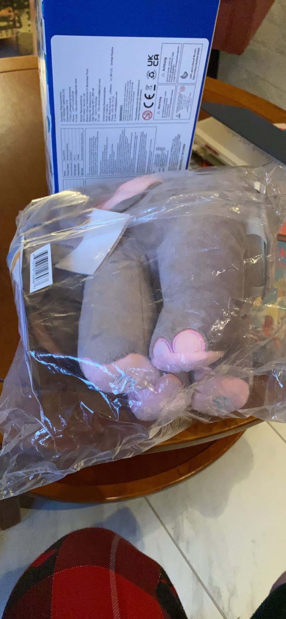 Plush toy elephant in clear plastic packaging with a box in the background