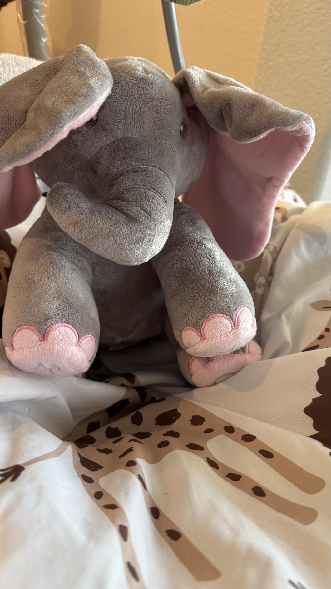 Gray plush elephant toy with pink accents on a patterned blanket