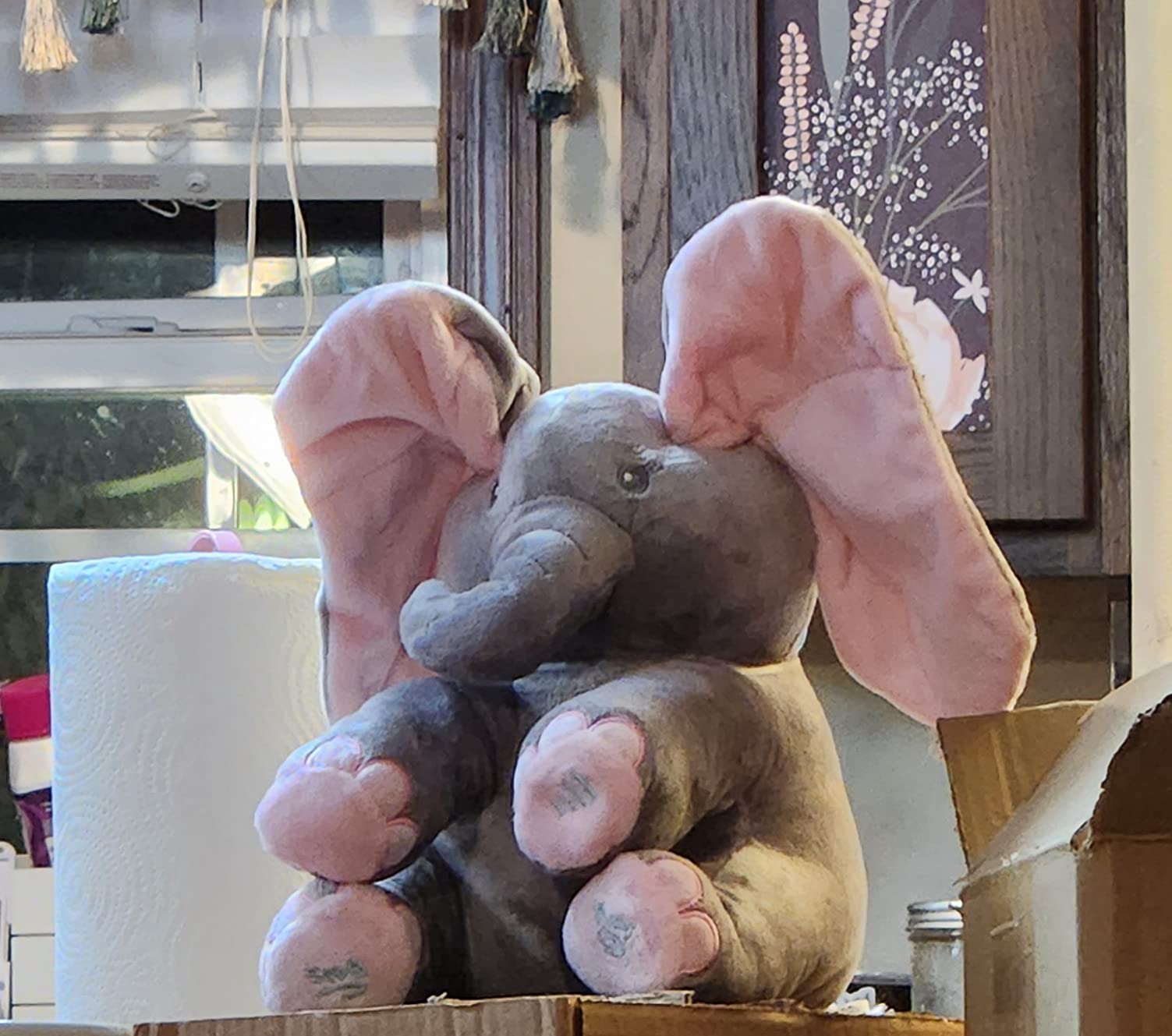 Plush elephant toy with pink ears in a kitchen setting