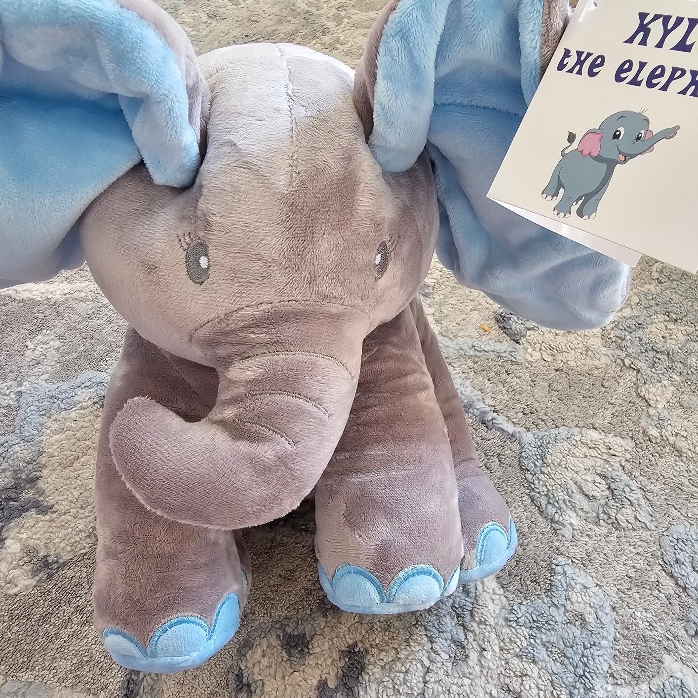 Plush elephant toy with blue accents on a textured surface