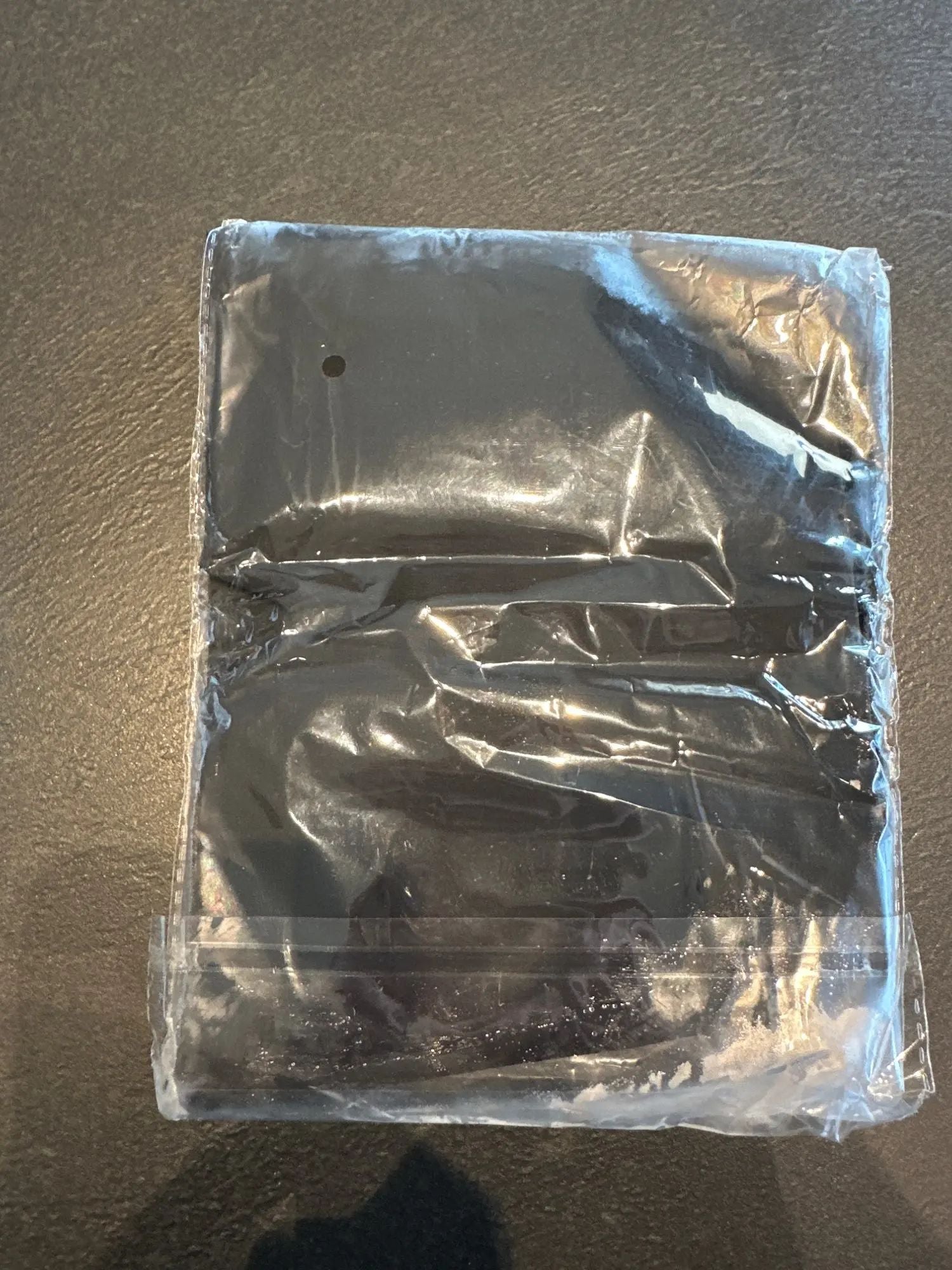 Clear plastic bag with a black object inside on a brown surface