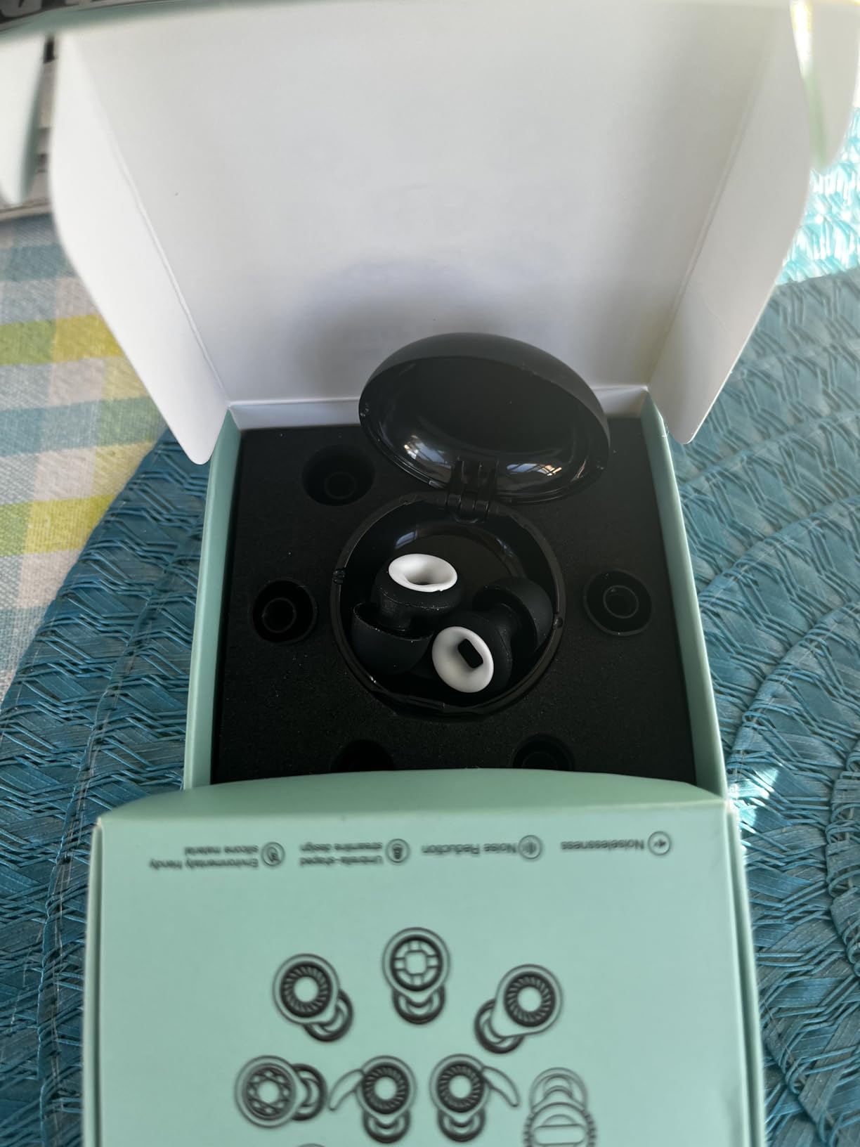 Black electronic device with white components inside an open box on a textured surface.