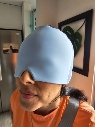 Person wearing a blue sleep mask indoors with a neutral background